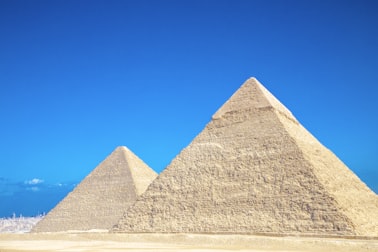 Two pyramids in the desert under a bright blue sky