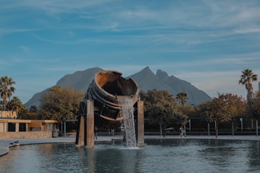 A fountain sculpture in a park in Monterrey, with mountains behind